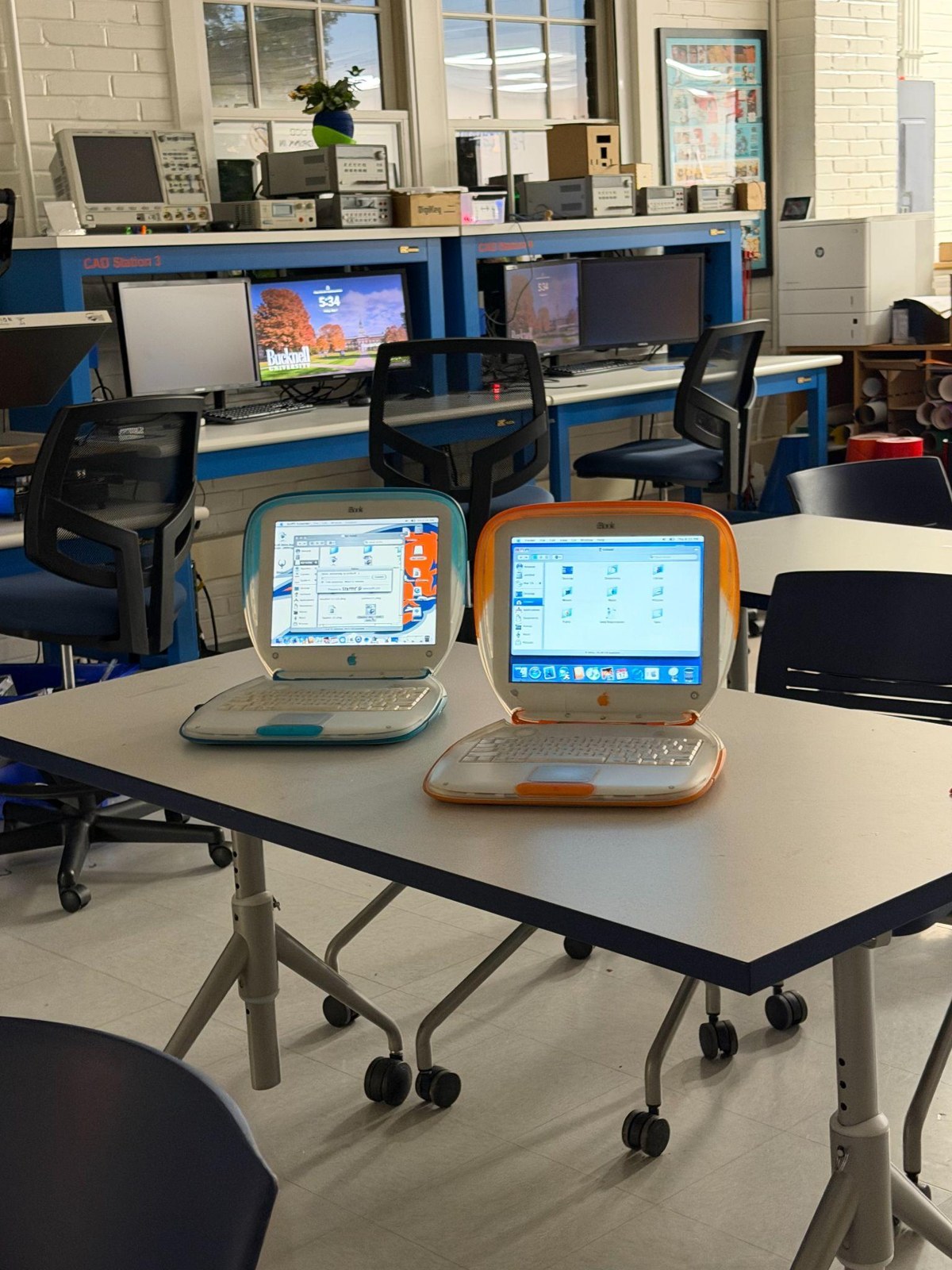 Restored blue and orange iBook G3 Clamshell laptops running on a workbench