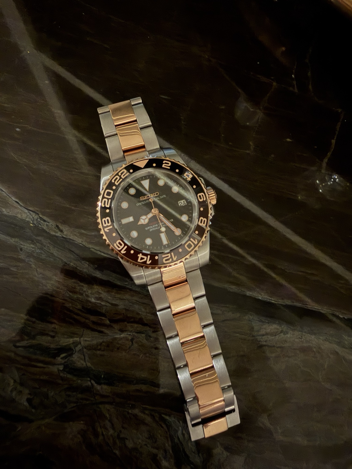 Root Beer Seiko mod with a black dial, brown-and-black bezel, and two-tone bracelet